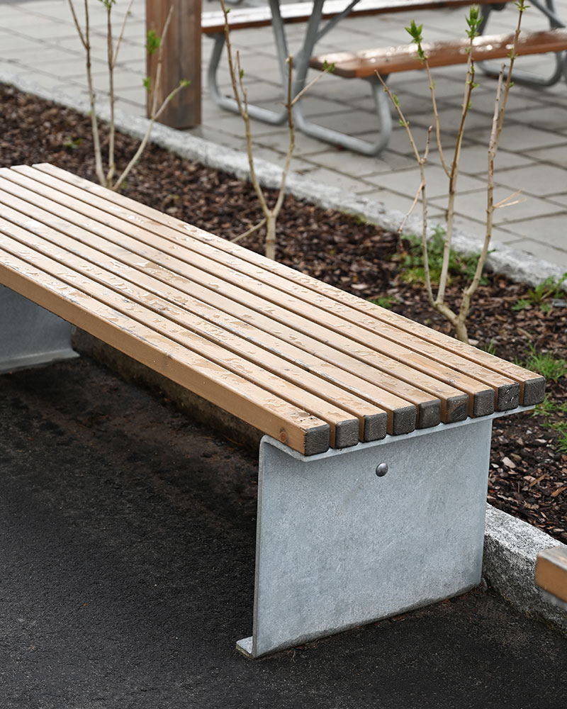 An outdoor bench with wooden slats and steel frame in an urban environment.